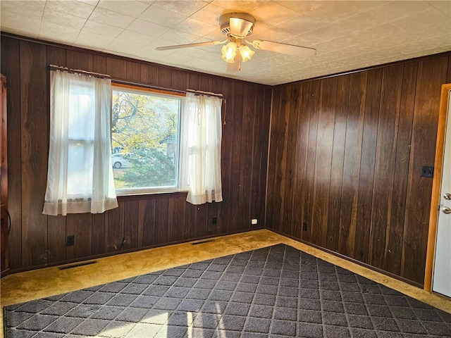 unfurnished room with ceiling fan, light colored carpet, and wooden walls