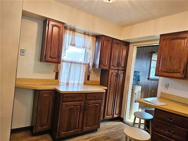 kitchen with dark brown cabinetry, a textured ceiling, and hardwood / wood-style flooring