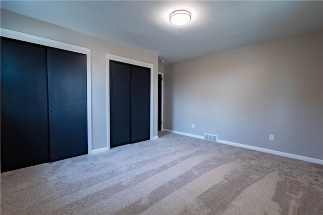 unfurnished bedroom featuring carpet floors and two closets