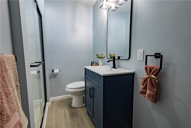 bathroom with hardwood / wood-style floors, vanity, a shower with shower door, and toilet