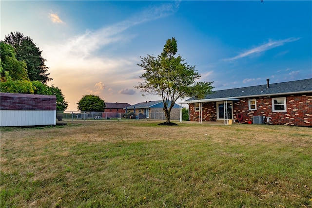 yard at dusk featuring a storage shed and central air condition unit