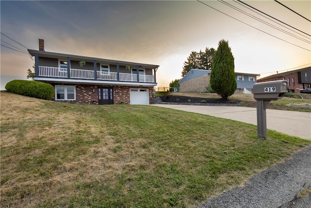 front of property with a yard, a balcony, and a garage