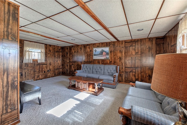 living room featuring a paneled ceiling, wood walls, and carpet