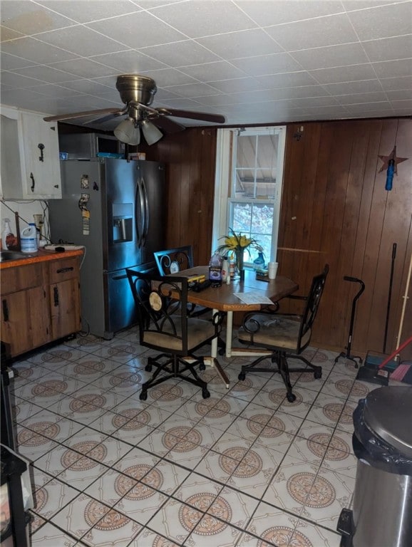 dining area with wood walls and ceiling fan