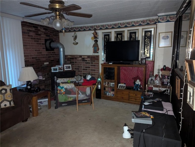 living room with concrete flooring, a wood stove, ceiling fan, and brick wall