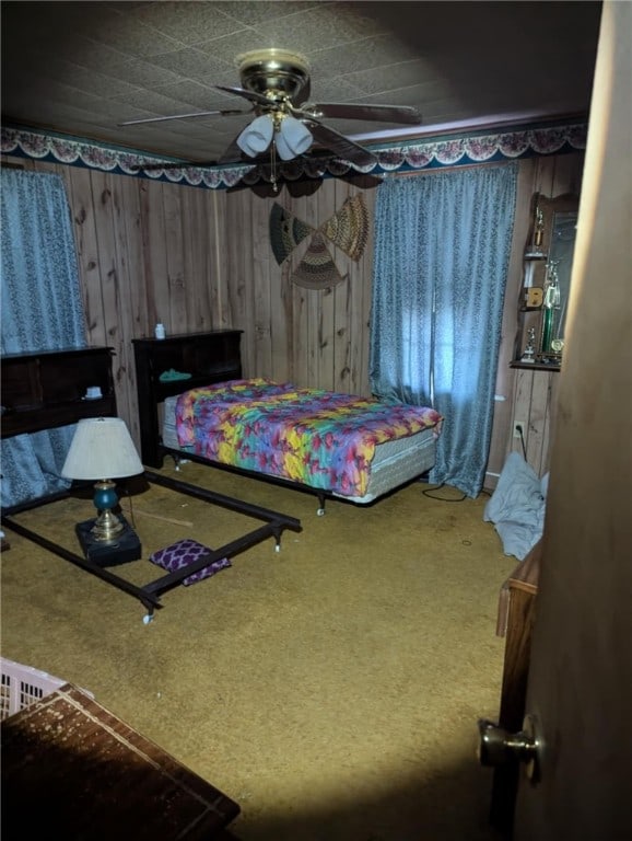 carpeted bedroom featuring ceiling fan and wood walls