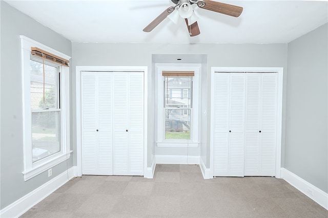 unfurnished bedroom featuring light carpet and two closets