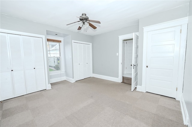 unfurnished bedroom featuring ceiling fan and multiple closets