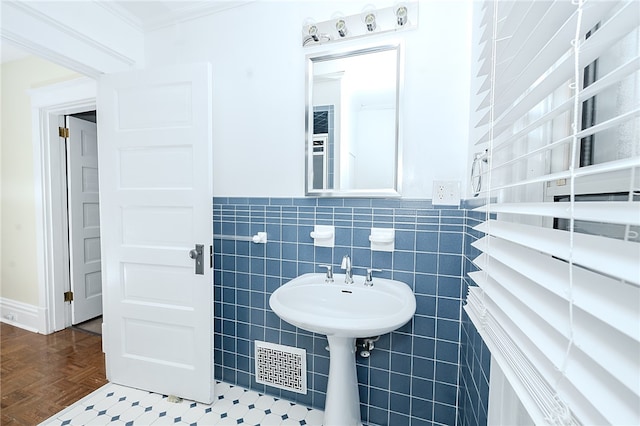 bathroom with parquet floors, ornamental molding, and tile walls