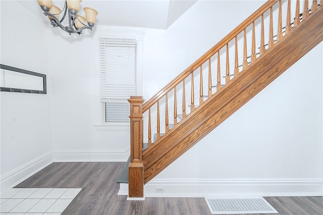 stairway with hardwood / wood-style floors and a notable chandelier