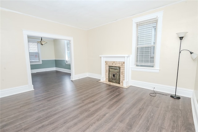 unfurnished living room featuring a tiled fireplace, crown molding, and dark hardwood / wood-style floors