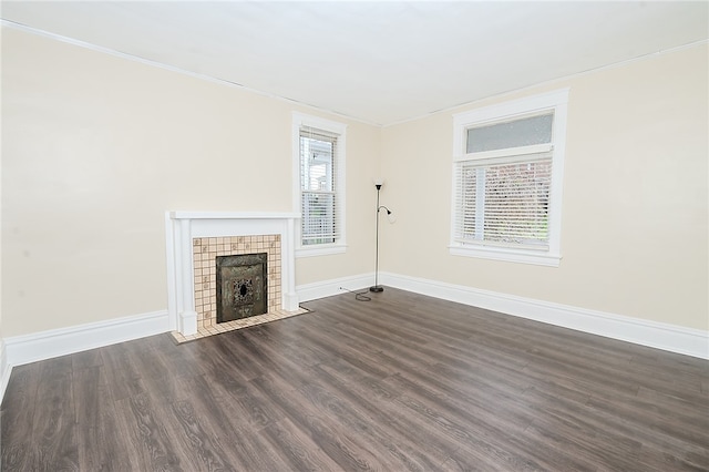 unfurnished living room featuring a tile fireplace, dark hardwood / wood-style flooring, and crown molding