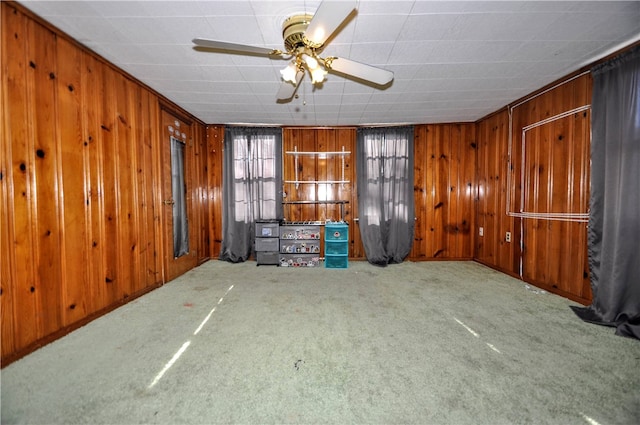 interior space featuring ceiling fan, carpet floors, and wooden walls