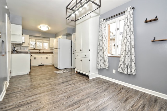 kitchen featuring tasteful backsplash, white cabinets, wood-type flooring, and white refrigerator