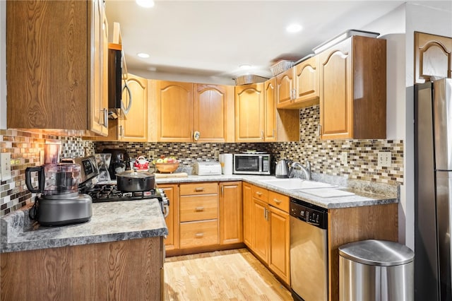 kitchen with decorative backsplash, sink, light wood-type flooring, and stainless steel appliances