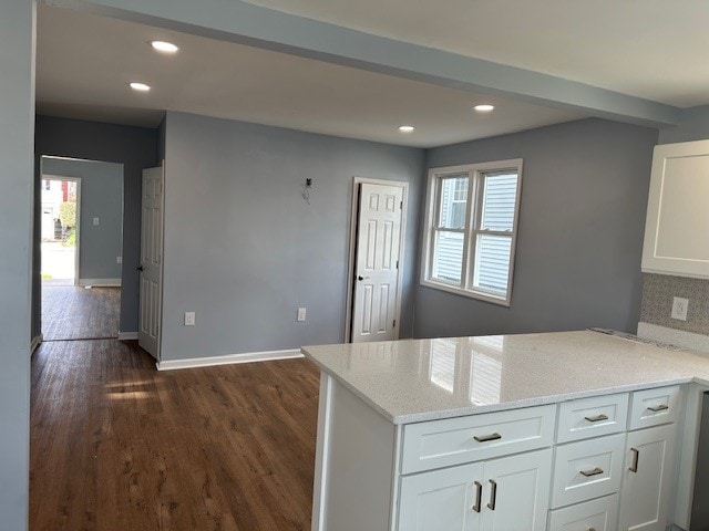 kitchen with white cabinetry, light stone countertops, dark hardwood / wood-style floors, backsplash, and kitchen peninsula