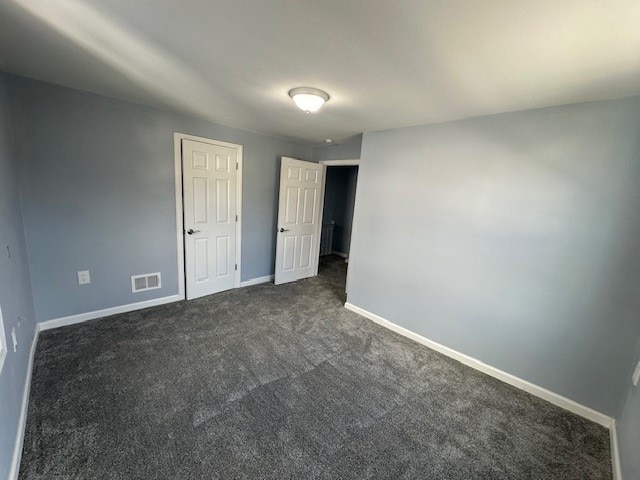 unfurnished bedroom with dark carpet