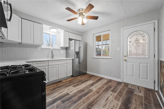 kitchen featuring stainless steel fridge, sink, black range, white cabinets, and dark hardwood / wood-style floors