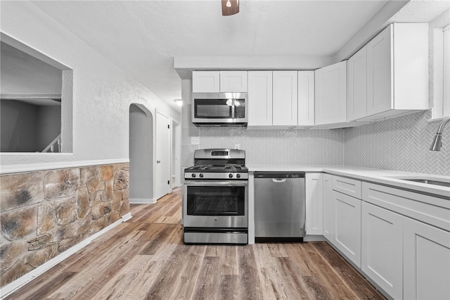 kitchen featuring white cabinets, sink, hardwood / wood-style flooring, appliances with stainless steel finishes, and tasteful backsplash