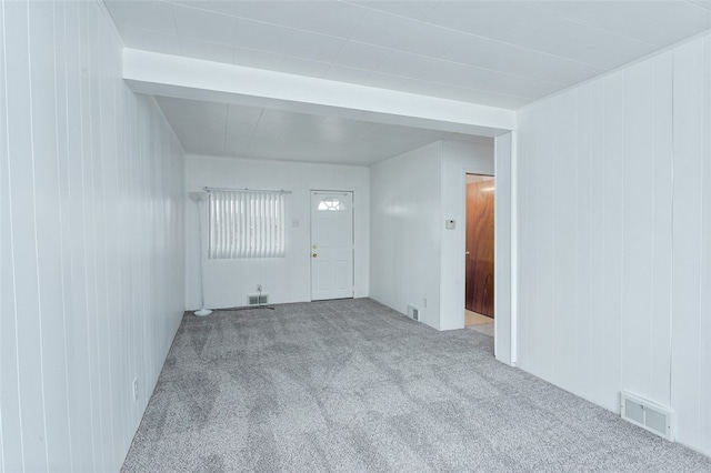 carpeted spare room featuring wooden walls