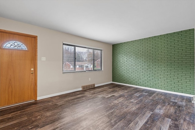 entrance foyer featuring dark wood-type flooring and brick wall