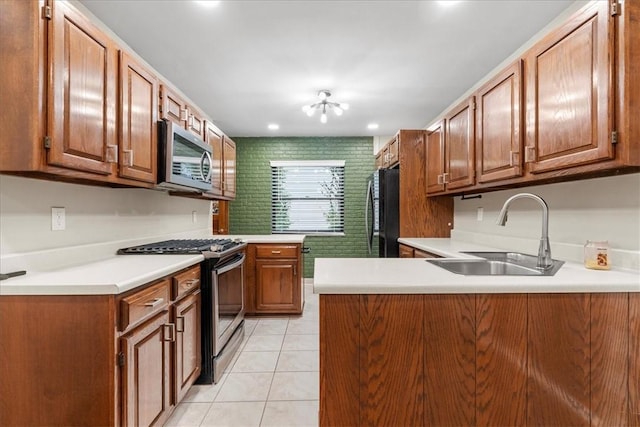 kitchen with kitchen peninsula, refrigerator, range with gas cooktop, sink, and light tile patterned floors