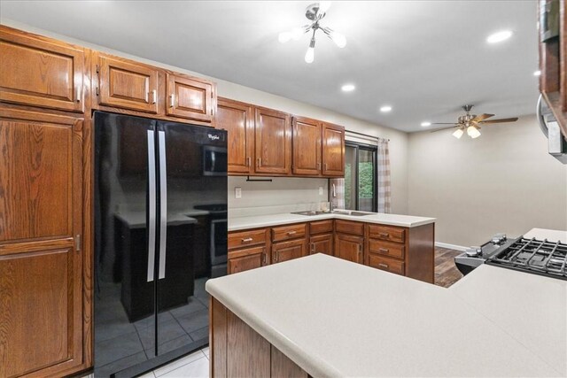 kitchen featuring ceiling fan, sink, black fridge, kitchen peninsula, and light tile patterned floors