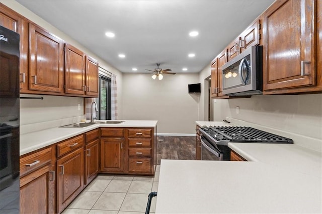 kitchen with ceiling fan, sink, kitchen peninsula, light tile patterned floors, and appliances with stainless steel finishes