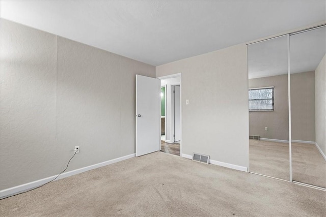 unfurnished bedroom featuring light carpet and a closet