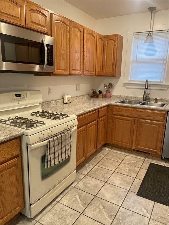 kitchen with light tile patterned flooring, hanging light fixtures, gas range gas stove, and sink