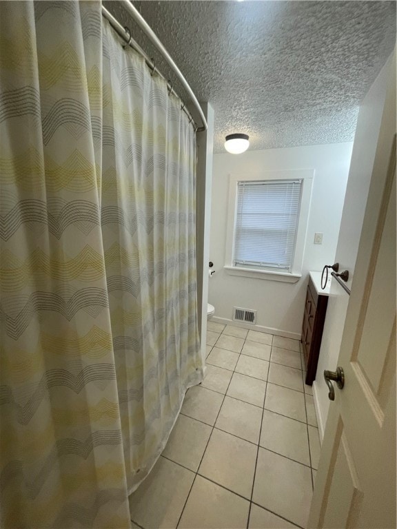 bathroom with tile patterned flooring, a textured ceiling, and toilet