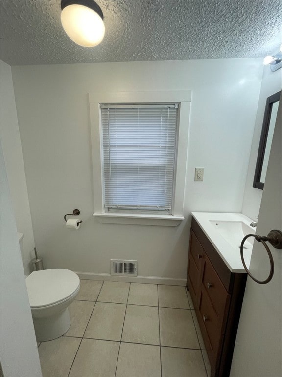 bathroom with tile patterned flooring, vanity, a textured ceiling, and toilet