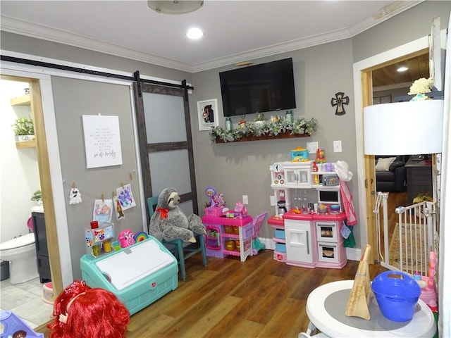 game room featuring a barn door, hardwood / wood-style flooring, and crown molding