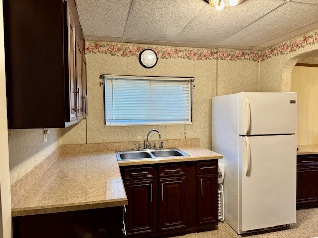 kitchen with a drop ceiling, white refrigerator, and sink