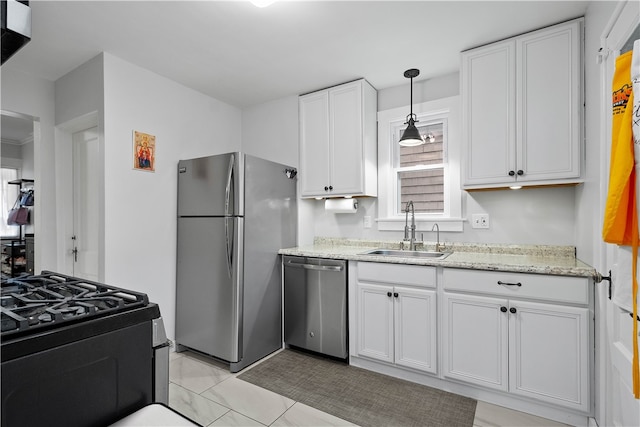 kitchen featuring hanging light fixtures, sink, light stone countertops, appliances with stainless steel finishes, and white cabinetry