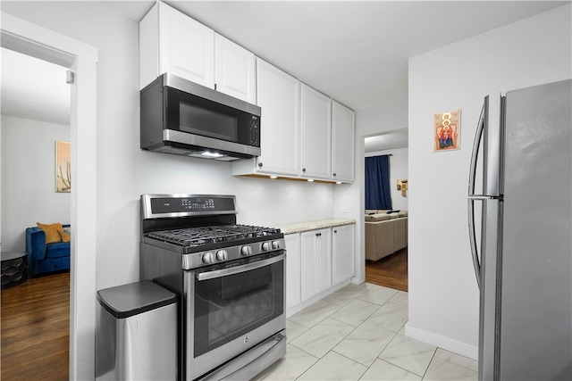 kitchen with white cabinets, light wood-type flooring, and appliances with stainless steel finishes