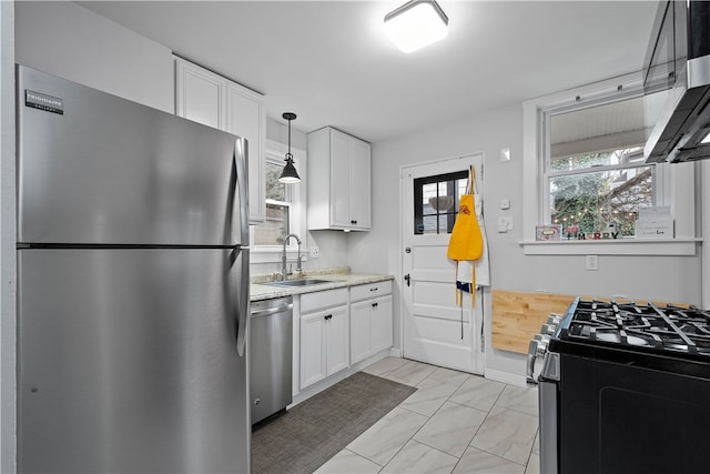 kitchen with white cabinets, appliances with stainless steel finishes, hanging light fixtures, and sink