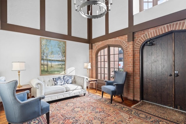 living room featuring hardwood / wood-style floors, a towering ceiling, a healthy amount of sunlight, and a notable chandelier