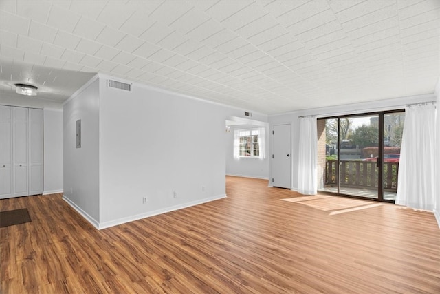 unfurnished living room with hardwood / wood-style floors and crown molding