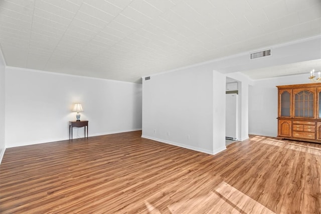 unfurnished living room featuring wood-type flooring, crown molding, and a chandelier