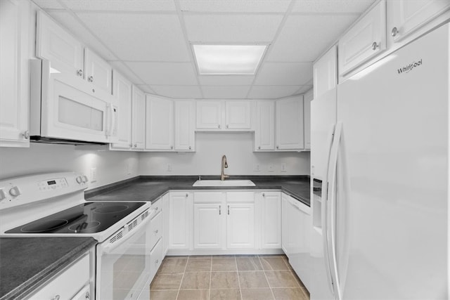 kitchen featuring a drop ceiling, white appliances, sink, light tile patterned floors, and white cabinets