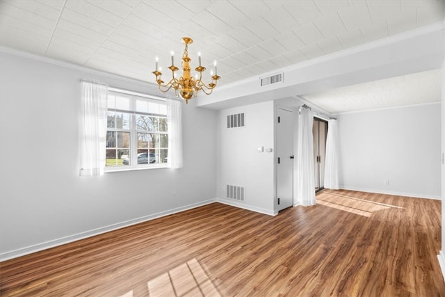 unfurnished room with hardwood / wood-style floors, crown molding, and a chandelier