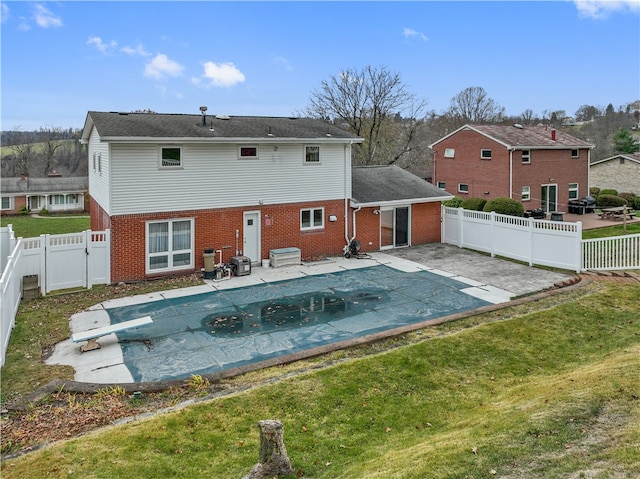 back of house with a patio, a covered pool, and a lawn