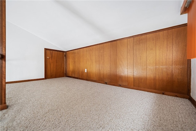 bonus room featuring light carpet, lofted ceiling, and wood walls