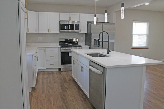 kitchen with a kitchen island with sink, white cabinets, hanging light fixtures, appliances with stainless steel finishes, and dark hardwood / wood-style flooring