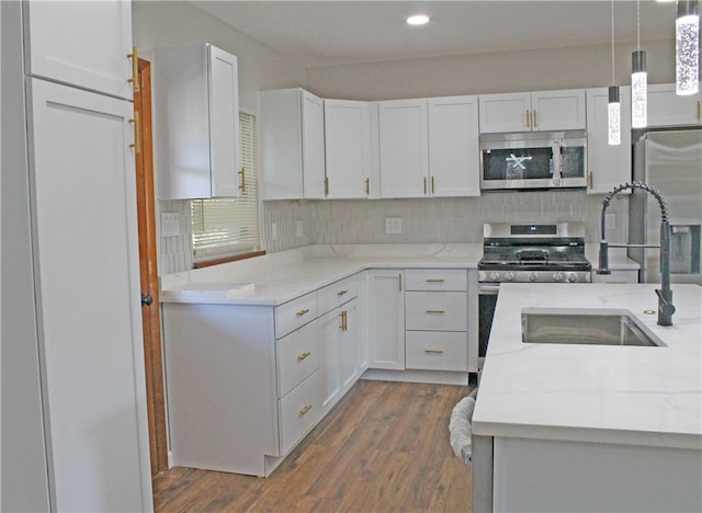 kitchen with white cabinetry, sink, stainless steel appliances, dark hardwood / wood-style flooring, and decorative light fixtures