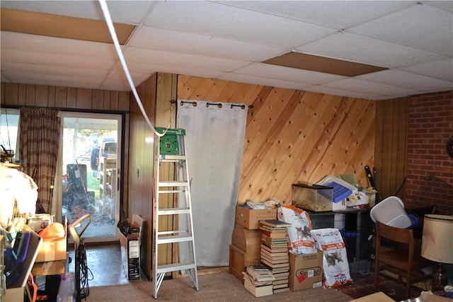 miscellaneous room with a paneled ceiling and wood walls