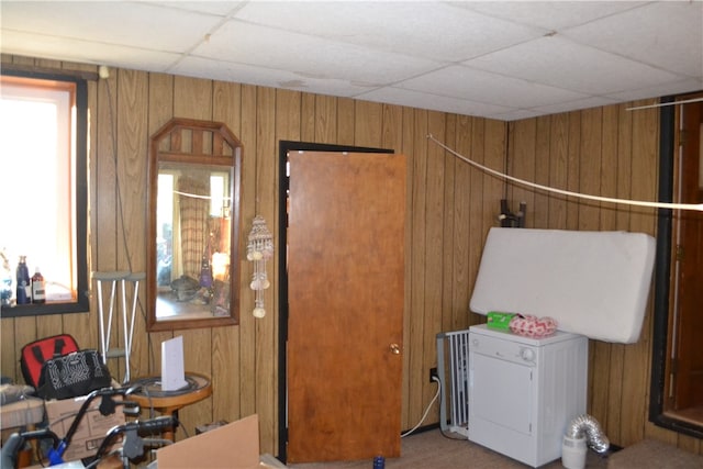 miscellaneous room featuring a drop ceiling and wooden walls