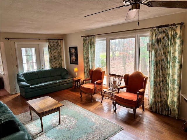 living room with hardwood / wood-style floors, plenty of natural light, ceiling fan, and a textured ceiling