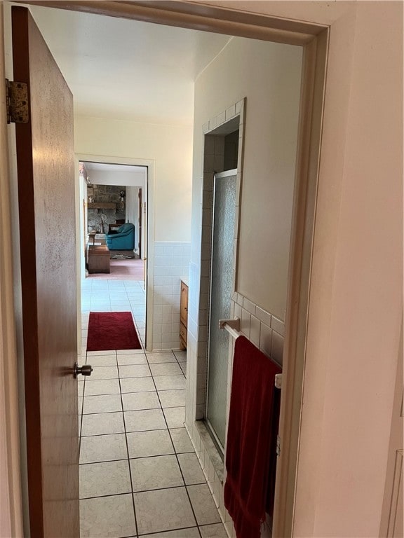 hall featuring light tile patterned floors and tile walls